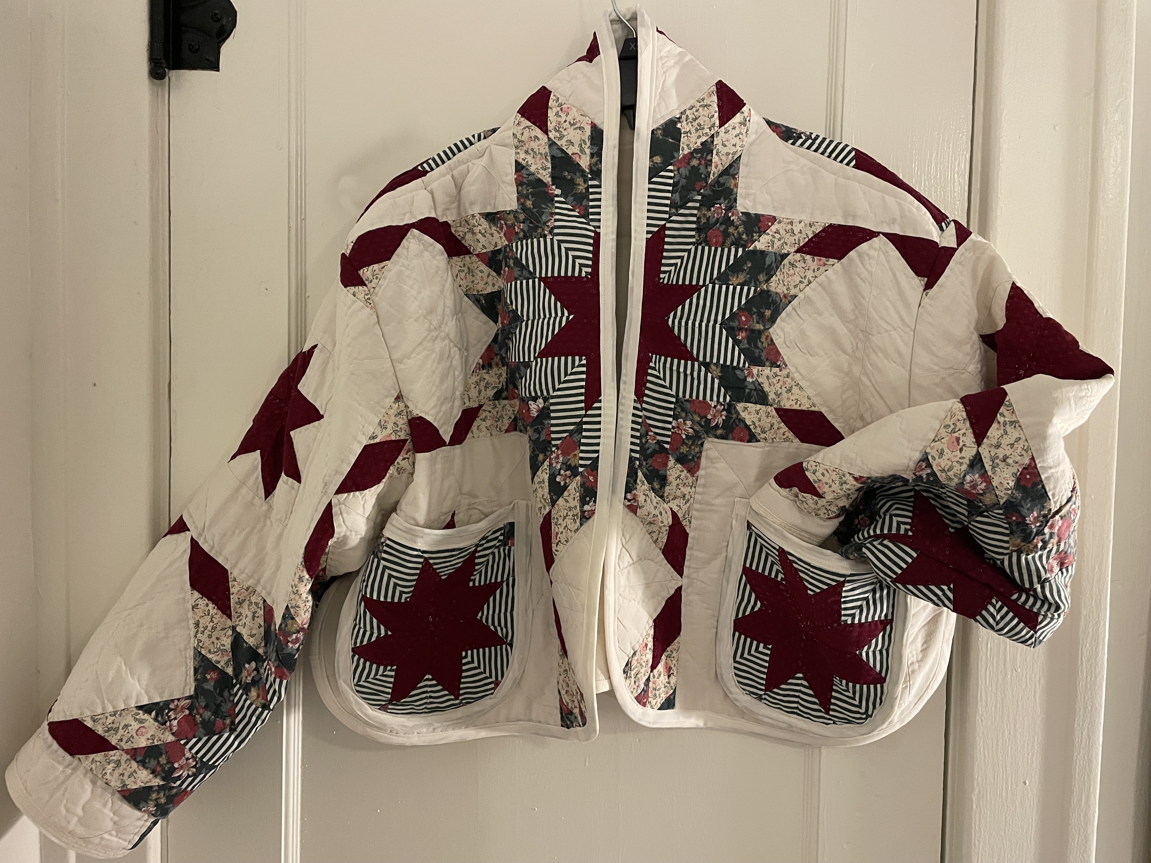 Maroon and cream star quilt coat hanging on a door